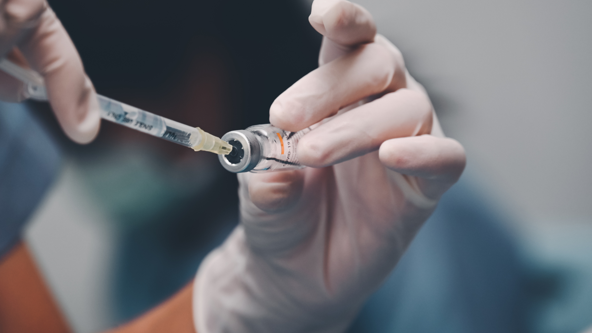 Gloved hand holding a vaccine vial