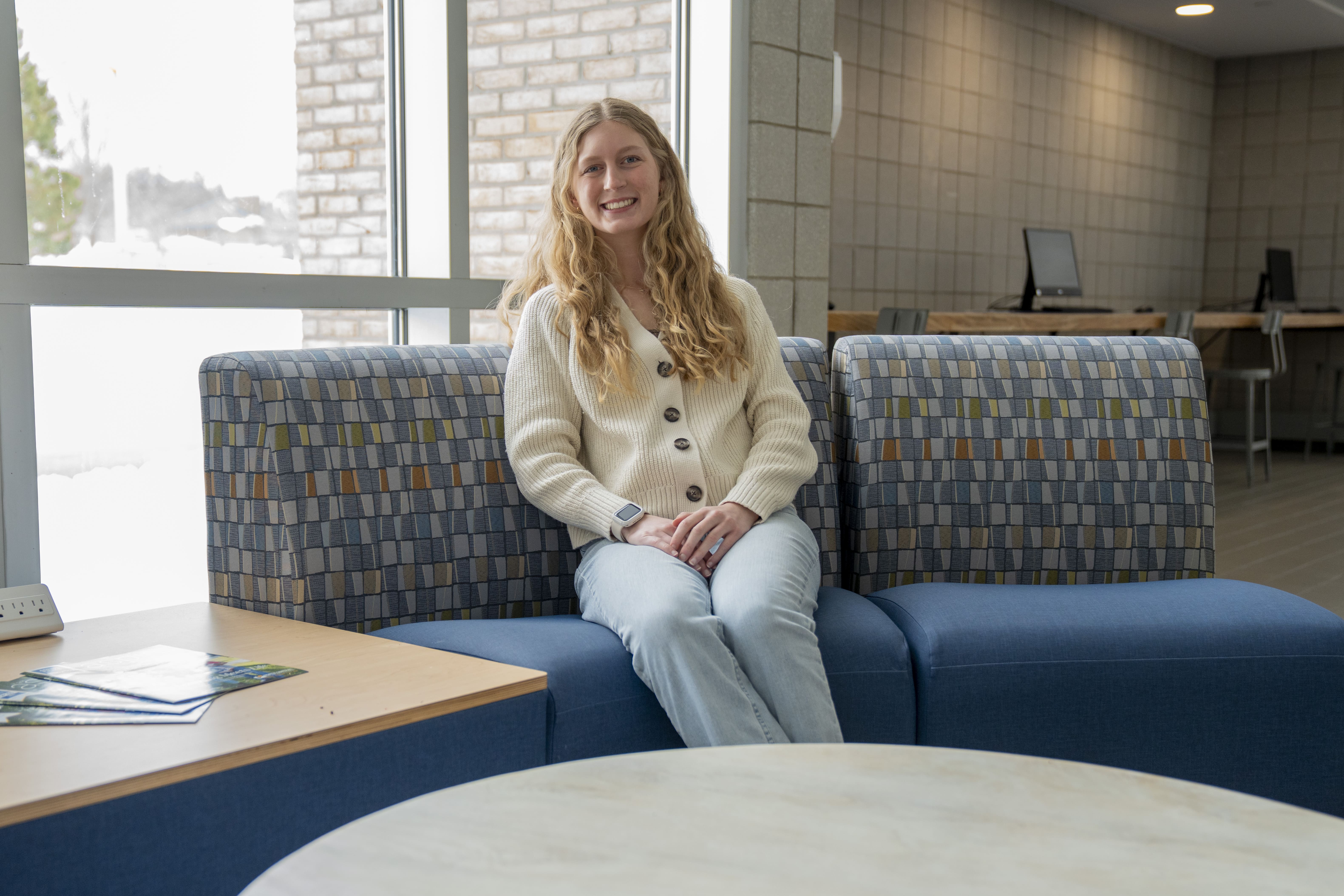 Rachel Pott sits on a couch inside a North Central Michigan College campus building.