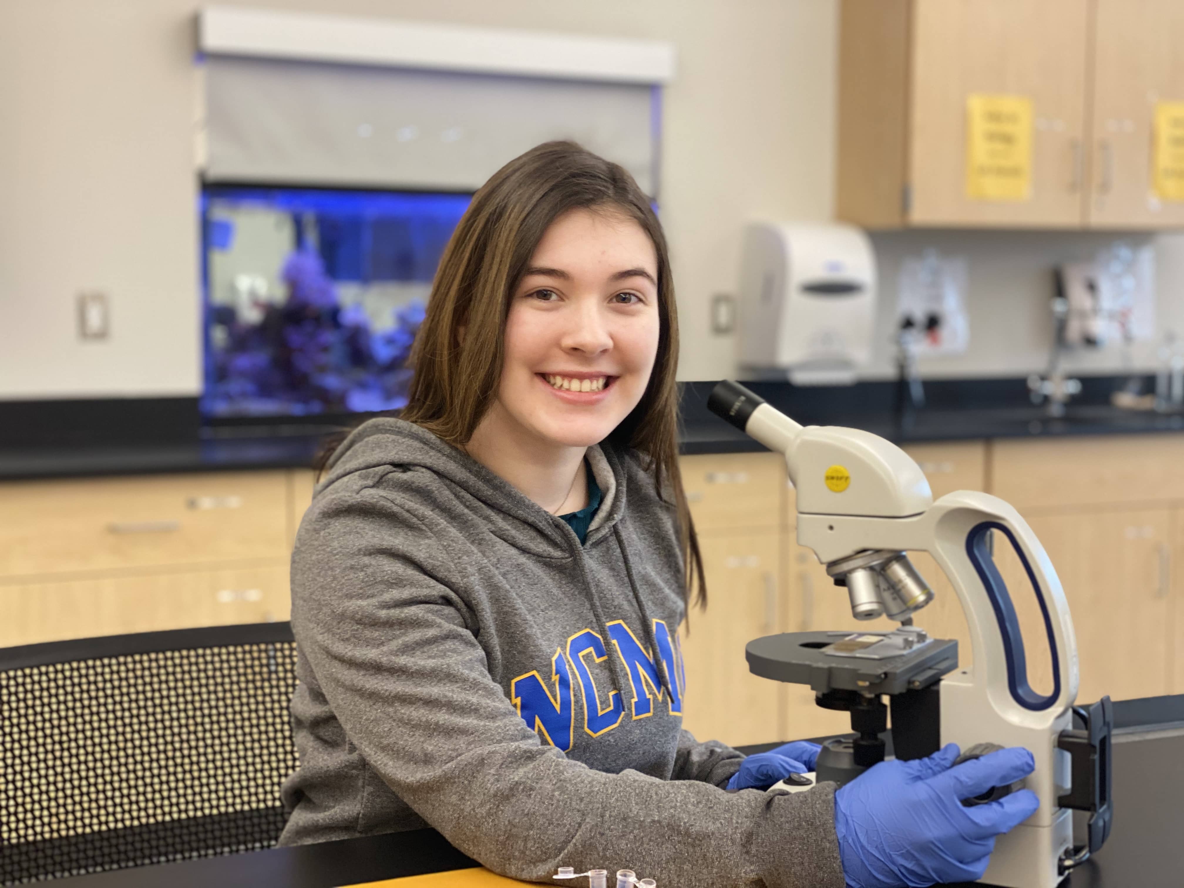 Female student at microscope, smiling