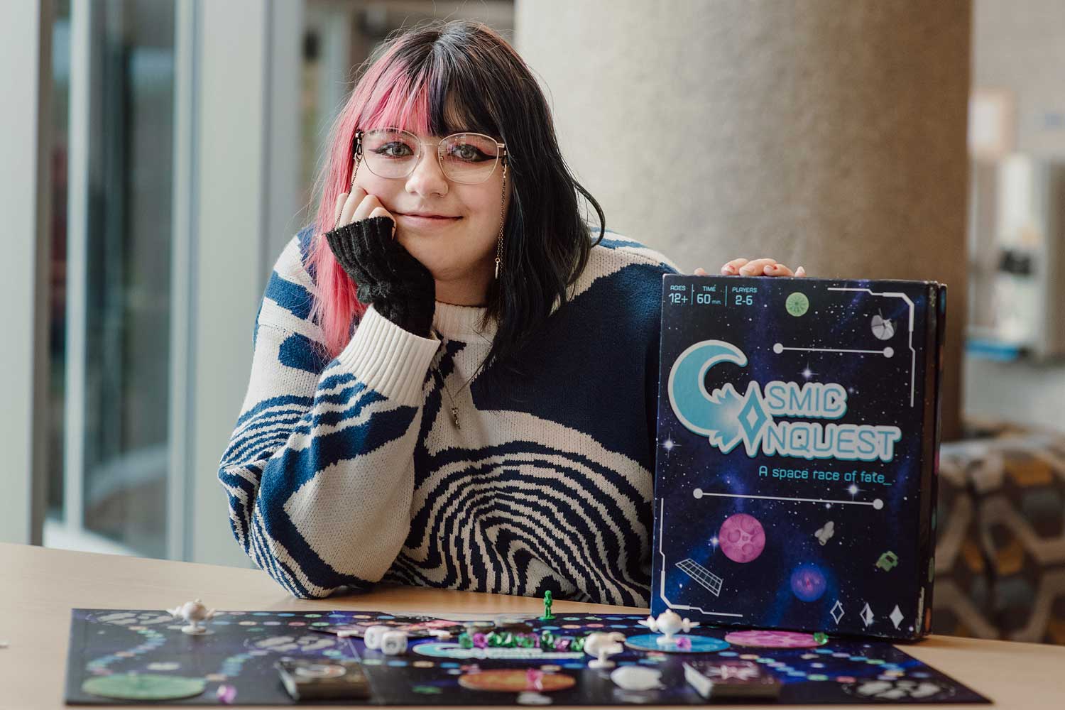 Student posing with arm resting on board game box