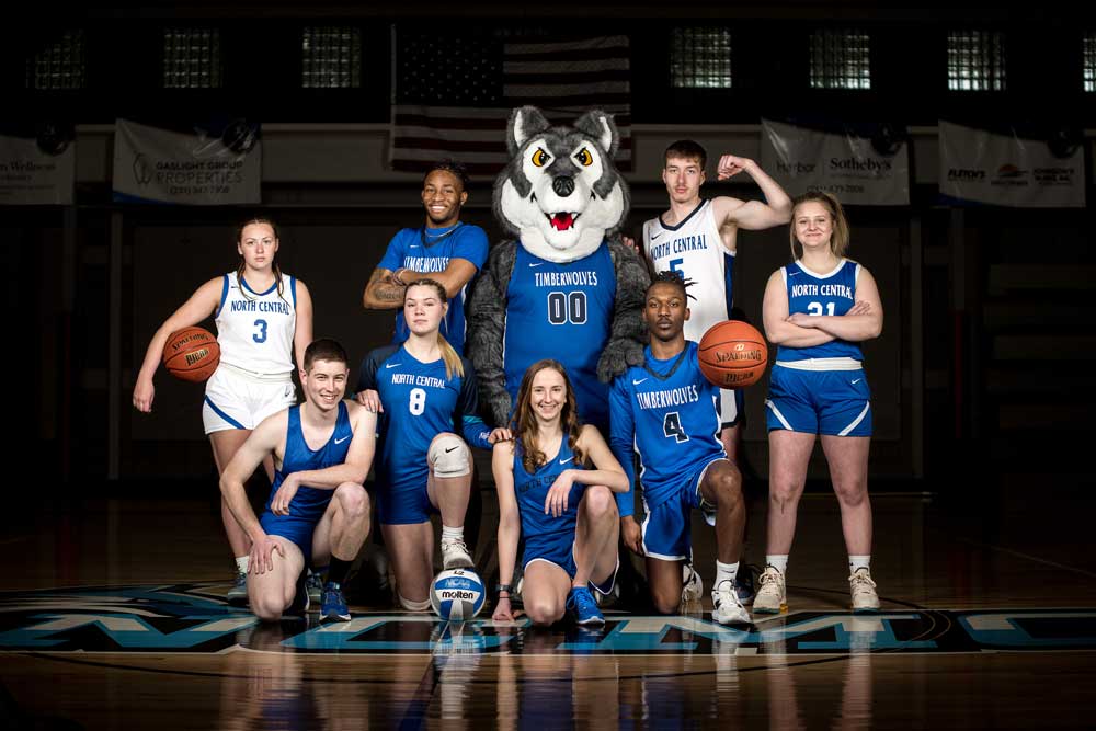 Group of NCMC student-athletes posing with Timberwolf mascot in Petoskey Plastics Arena