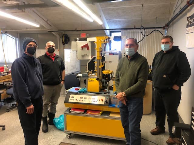 Individuals posing in front of machinery