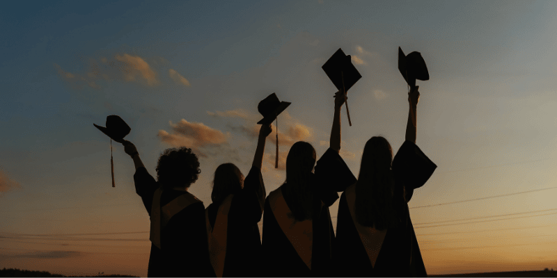 Graduates holding caps in air