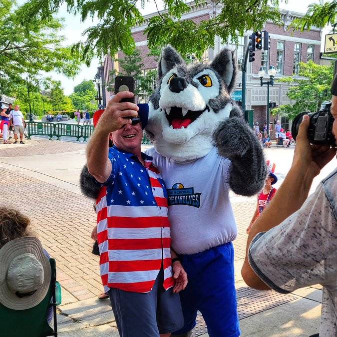 Man taking photo with North Central Timberwolf mascot