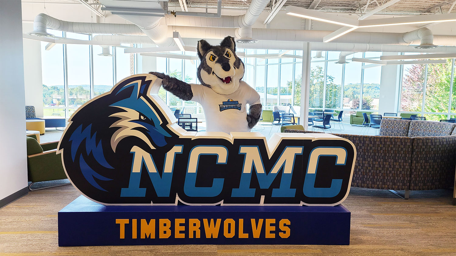 Timberwolf mascot standing in front of NCMC foam sculpture