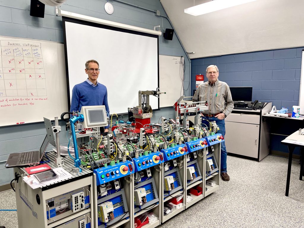Two instructors standing beside smart factory equipment