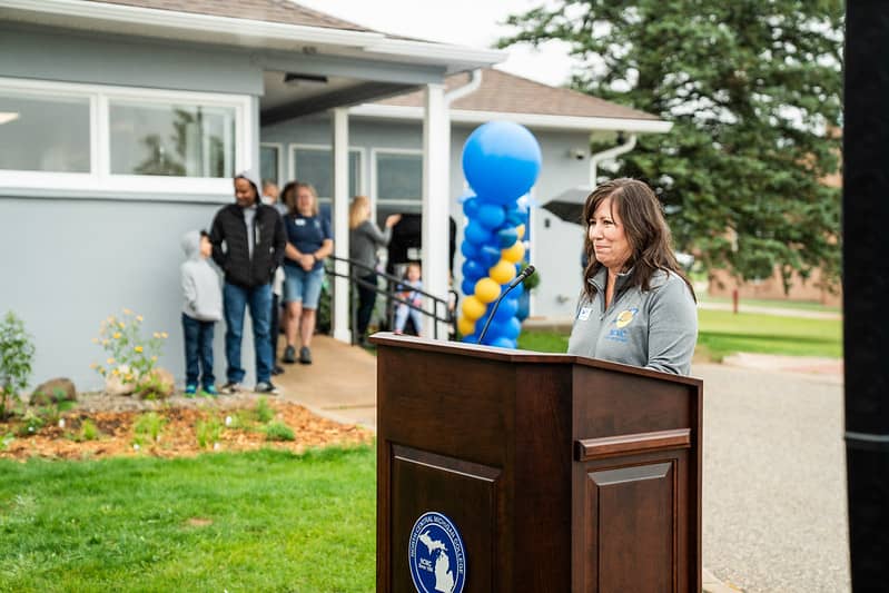 Jennifer Wixson stands at a podium addressing the audience at a college event with balloons and the NCMC Early Learning Center in the background