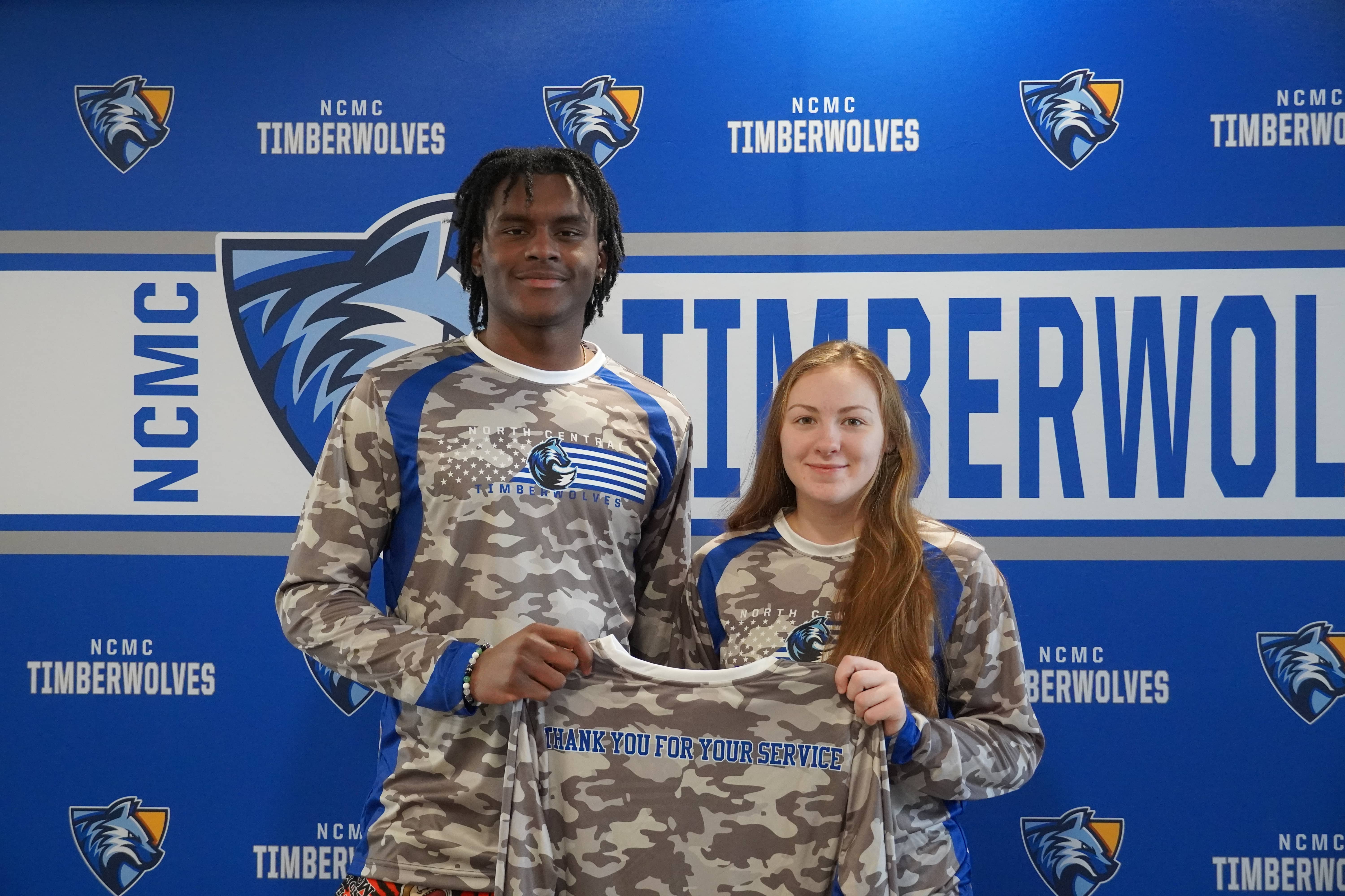 Two smiling basketball players wearing military appreciation warmups